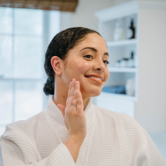 Woman applying CLN & DRTY Goodbye Acne Blemish Stick  to her face in a bathroom setting