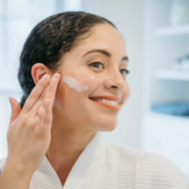 Woman applying cream to her face in a bathroom setting