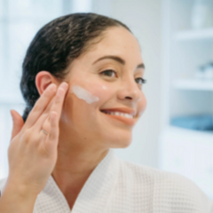 Woman applying cream to her face in a bathroom setting