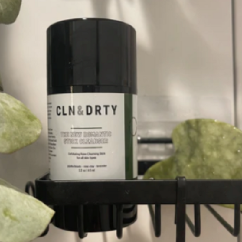 Cleanser bottle labeled 'CLN&DRTY' on a shelf with green leaves in the background