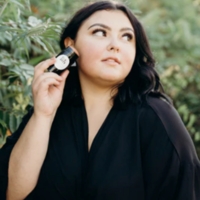 Woman holding a CLN & DRTY The New Romantic Cleansing Stick with a white label outdoors