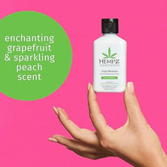 Hand holding a Hempz body wash bottle with a pink background and green text.